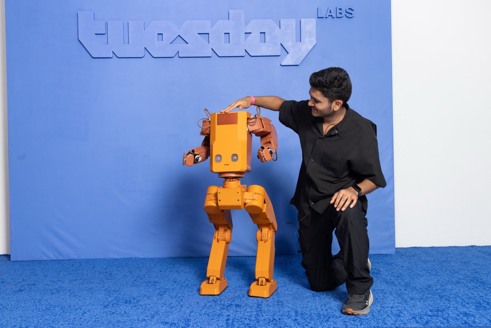 Sankalp kneeling beside Voxel with a hand on its head at the Tuesday Labs launch